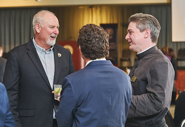 Brother Nathaniel Pierce, S.J.C. talks with others at an event focused on a key document in Catholic social teaching.
