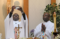 Father Richard Toboso, G.H.M. elevates the host as Father Charles Aketch, G.H.M. assists.