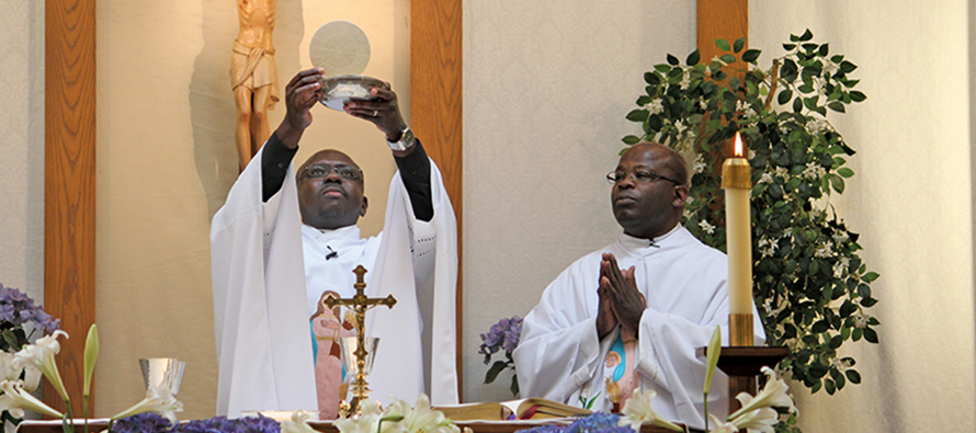 Father Richard Toboso, G.H.M. elevates the host as Father Charles Aketch, G.H.M. assists.