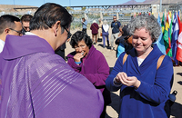 Sister Deirdre Griffin, S.S.J. receives Communion during a Mass held on a platform in the Rio Grande Canal between El Paso, Texas and Juárez, Mexico.