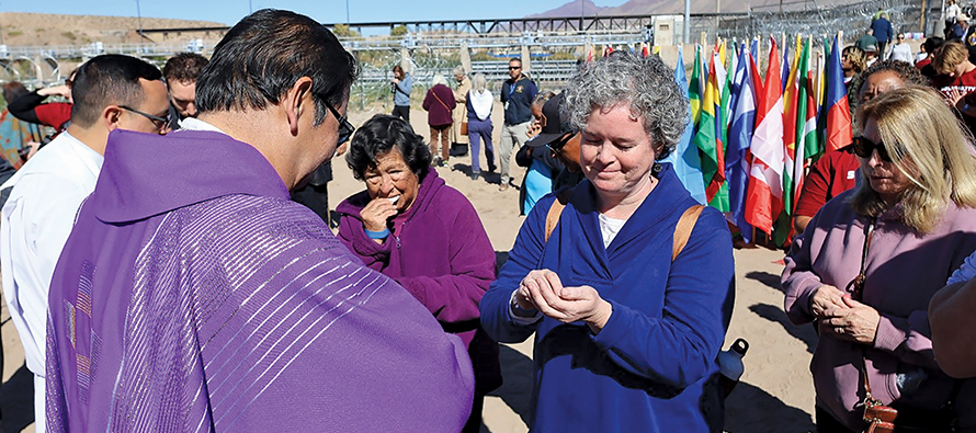Sister Deirdre Griffin, S.S.J. receives Communion during a Mass held on a platform in the Rio Grande Canal between El Paso, Texas and Juárez, Mexico.