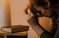 Woman praying with rosary beads