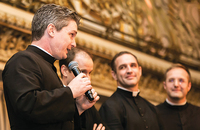 Brother Nathaniel Pierce, S.J.C. speaks during a benefit dinner alongside members of his community.